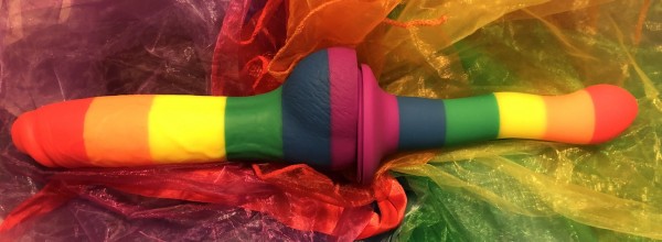 Colours Pride 8" and Wave dildos stuck together at their suction cups on bed of rainbow tulle