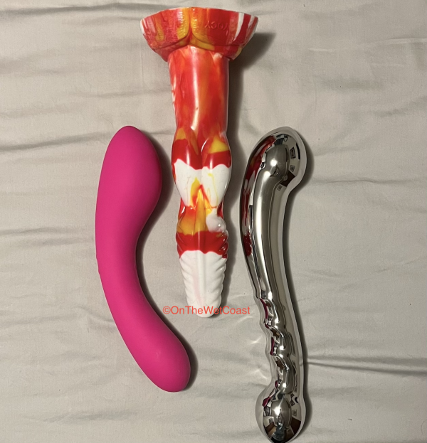 3 dildos lined up side by side - pink curved Swan Wand, Fenris Flame canine dildo, Njoy Eleven stainless steel