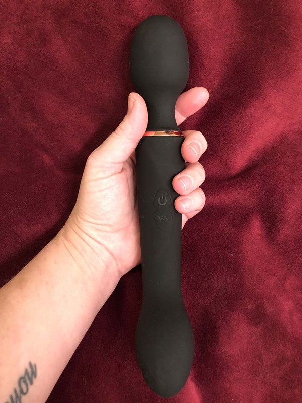 Kat's hand holding Lush Gia Wand vibrator above a red velour background